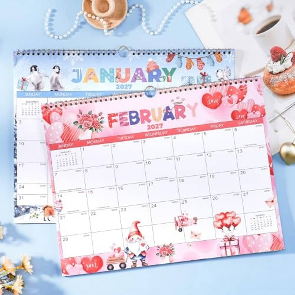 Wall calendar showing February 2027 page with pink hearts and gnome theme, spiral bound