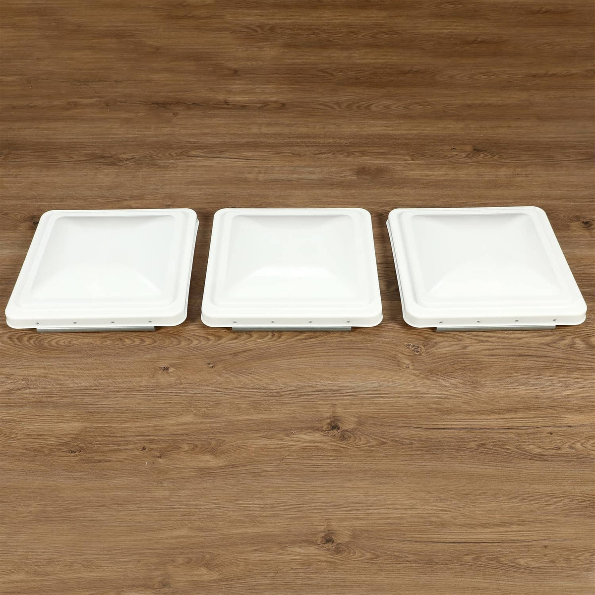 Three white RV roof vent cover lids lined up, square low-profile design