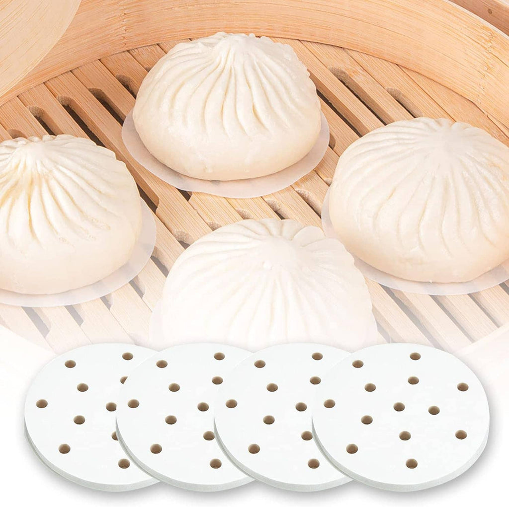 Steamed buns on round perforated white steamer liner pads laid over bamboo slats