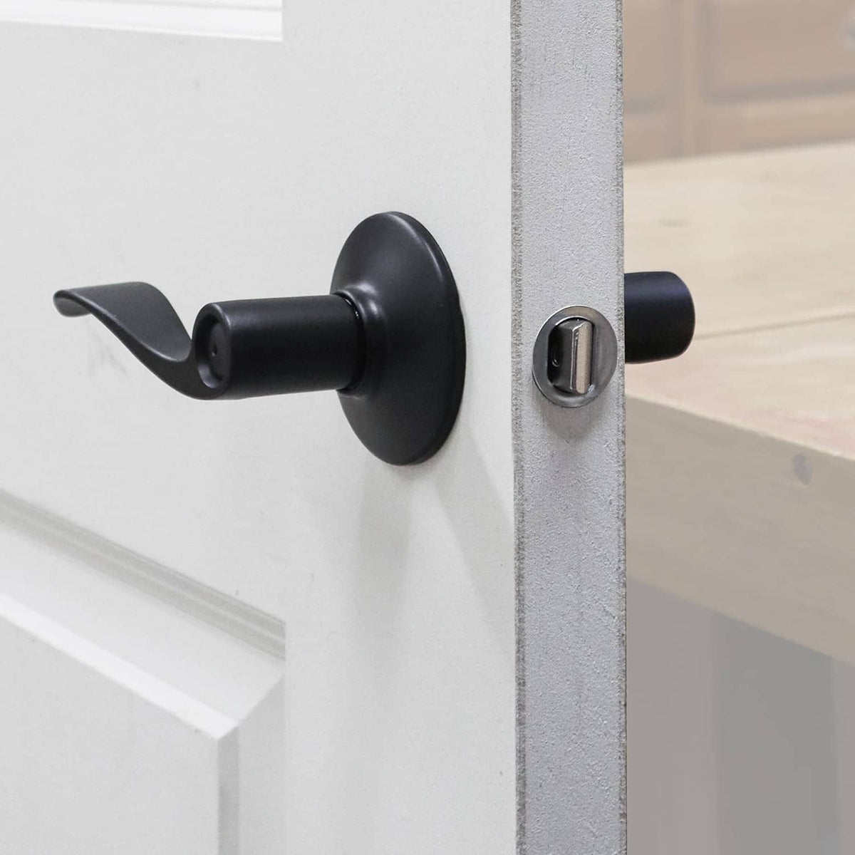 Black door lock handle and interior knob mounted on a drilled door panel