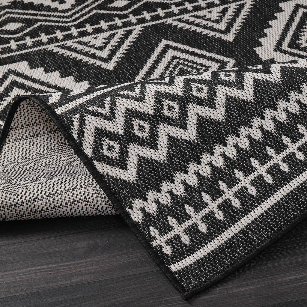 Rolled black-and-white geometric rug texture with diamond and zigzag pattern