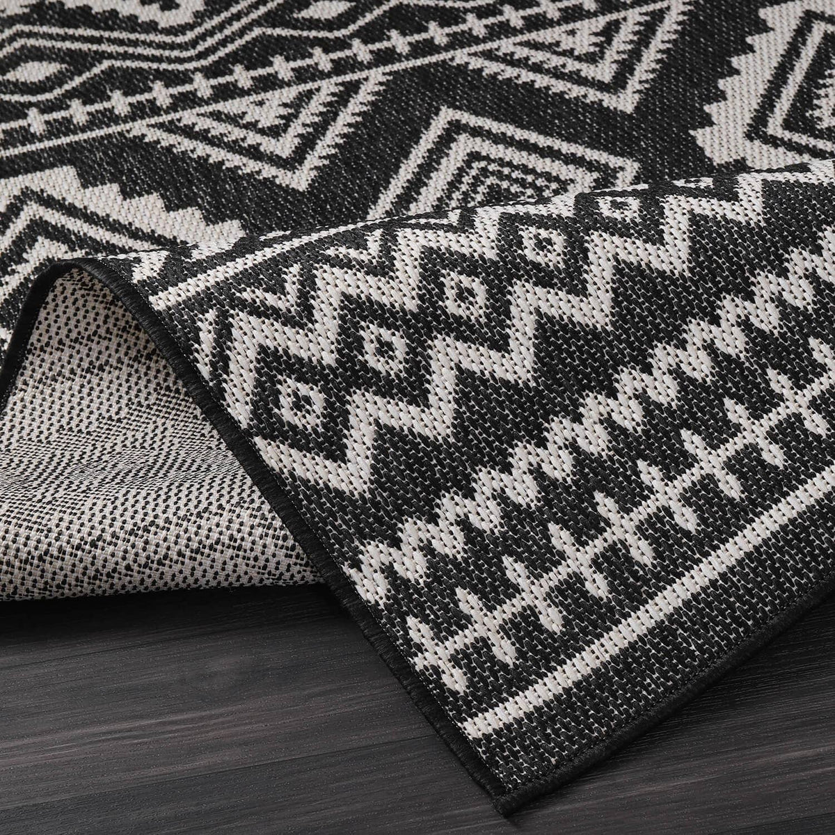 Rolled black-and-white geometric rug texture with diamond and zigzag pattern