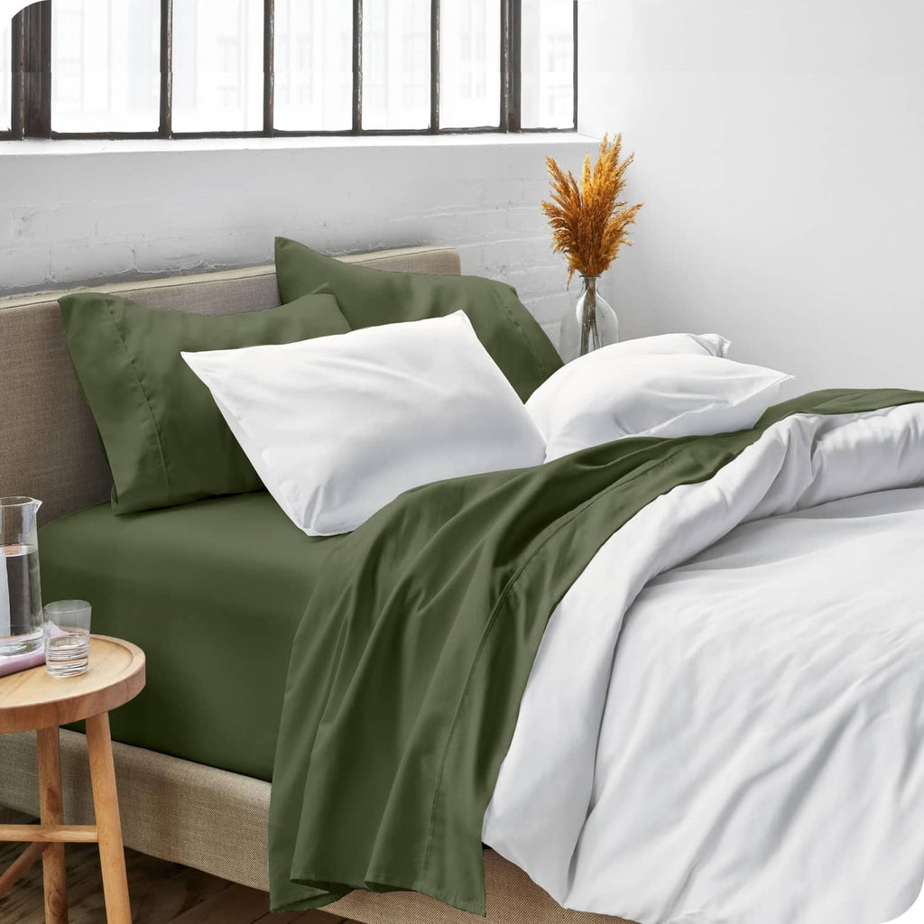 Olive green bed sheet set with pillowcases on a sofa bed with white linens