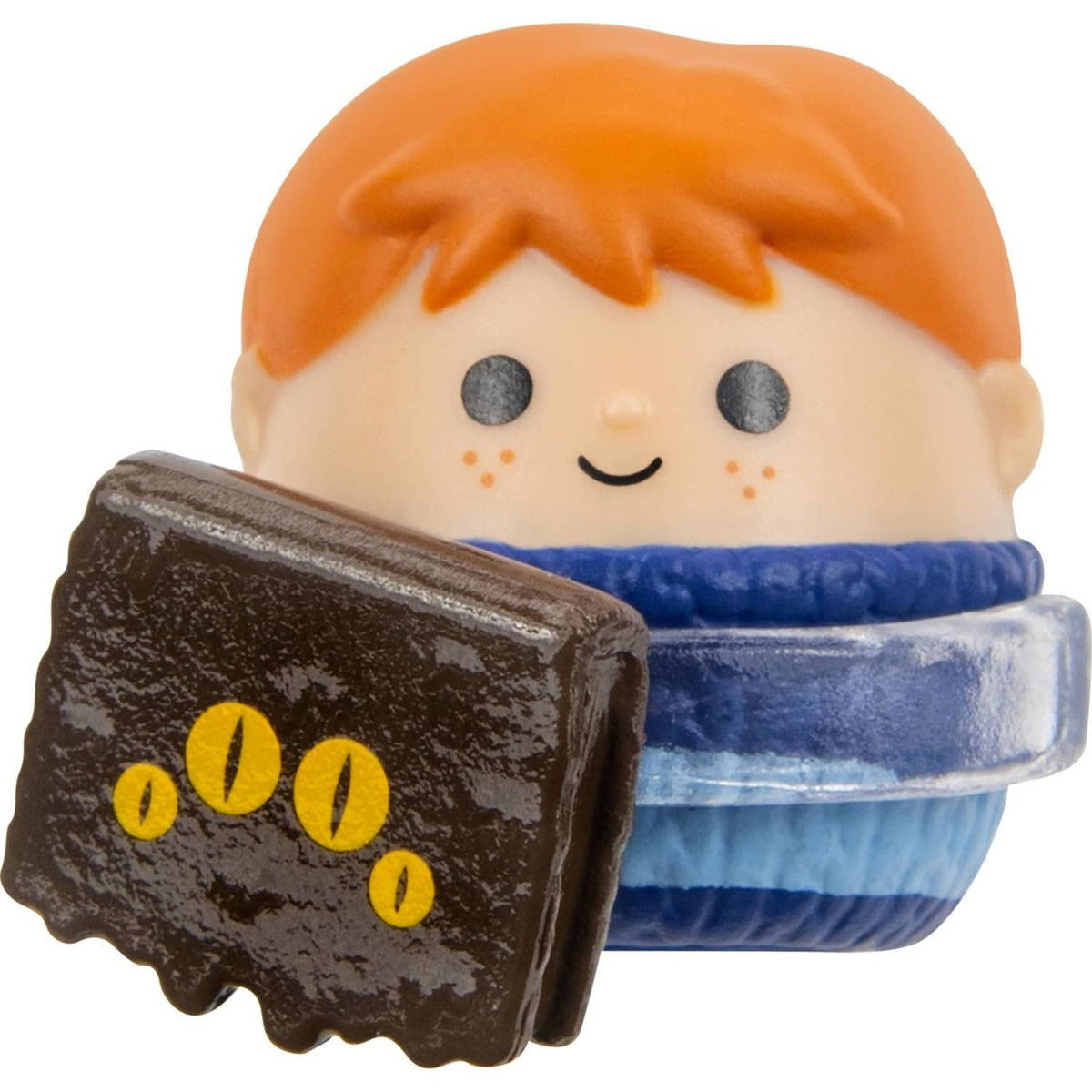 Mini squish toy figure with orange hair, blue base, and brown book accessory