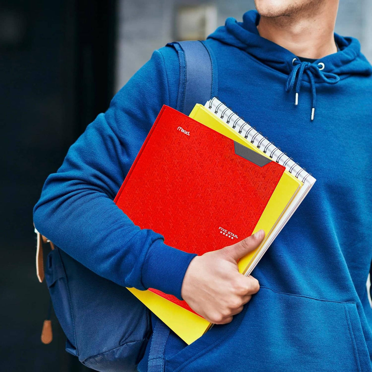 Person holding a red and yellow prong folder with lined pages