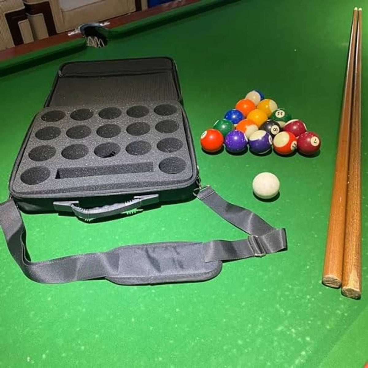 Hard pool ball carrying case on a billiard table, open lid with molded ball tray, dark gray.
