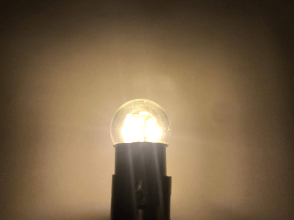 Lit miniature bulb with clear glass envelope and dark black base