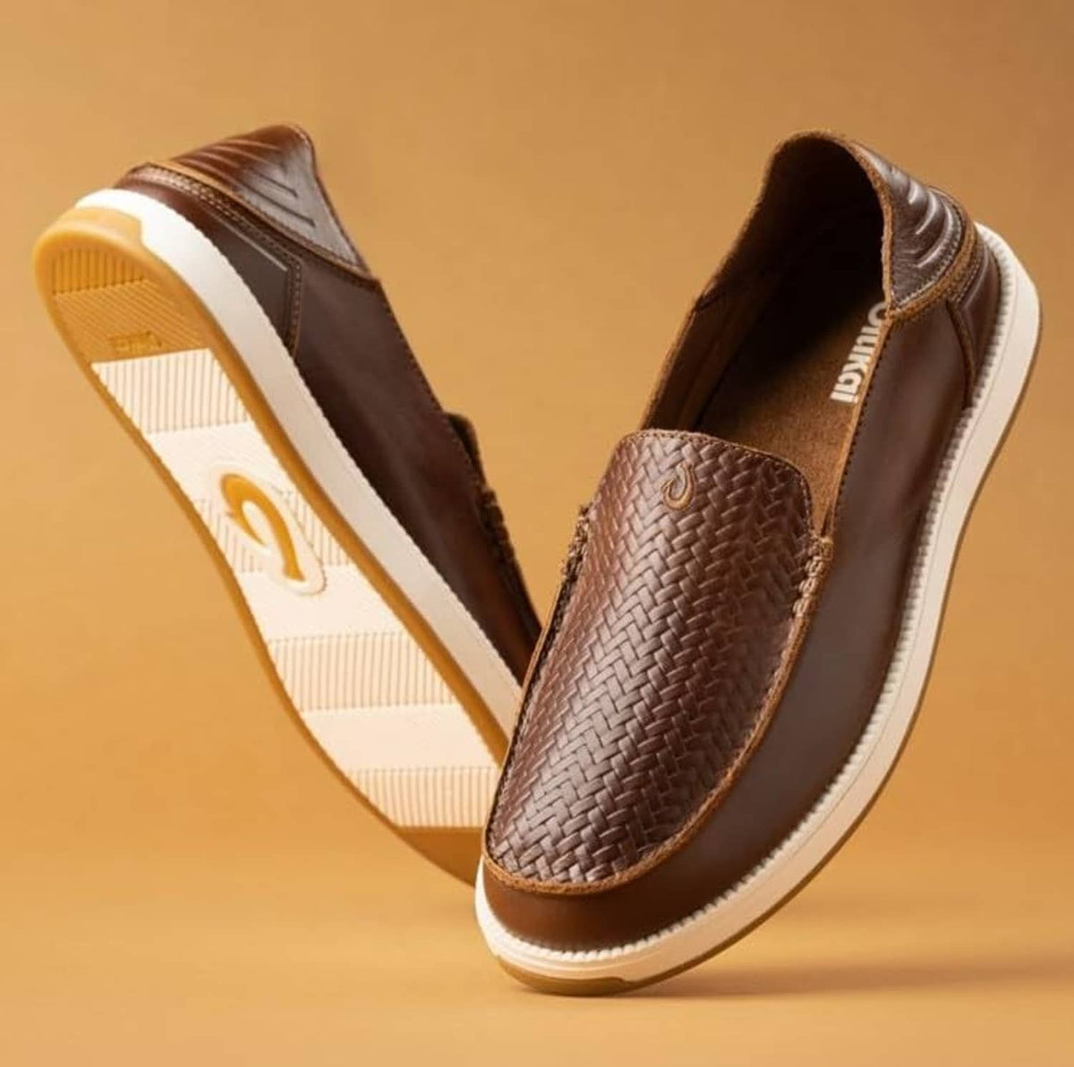 Brown leather slip-on sneakers shown angled, with woven toe and white rubber sole