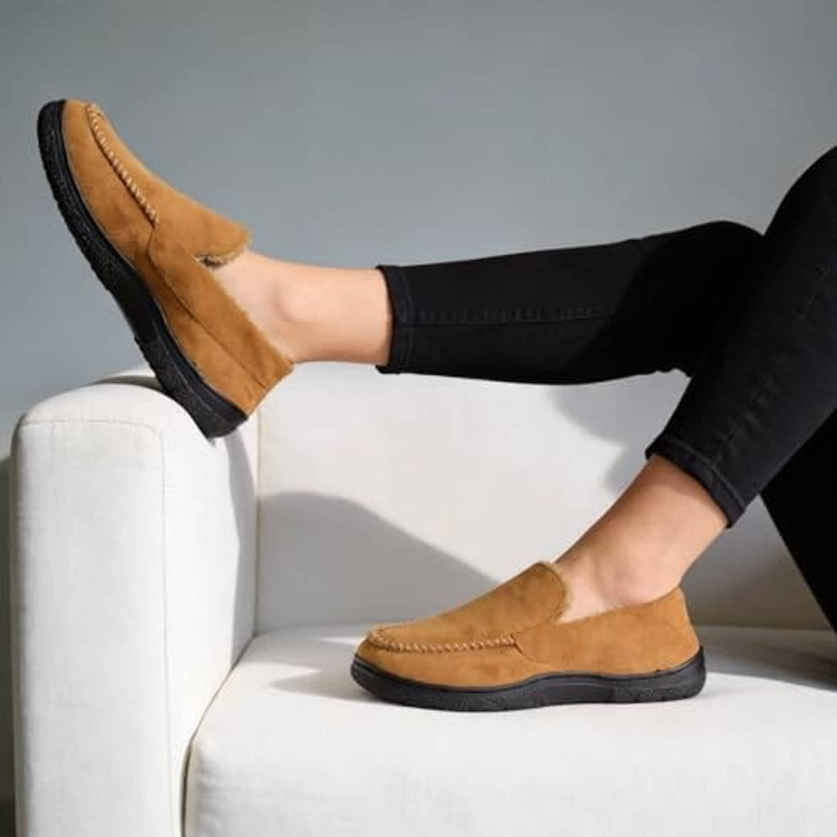 Brown moccasin slippers with plush lining and thick black sole worn by man