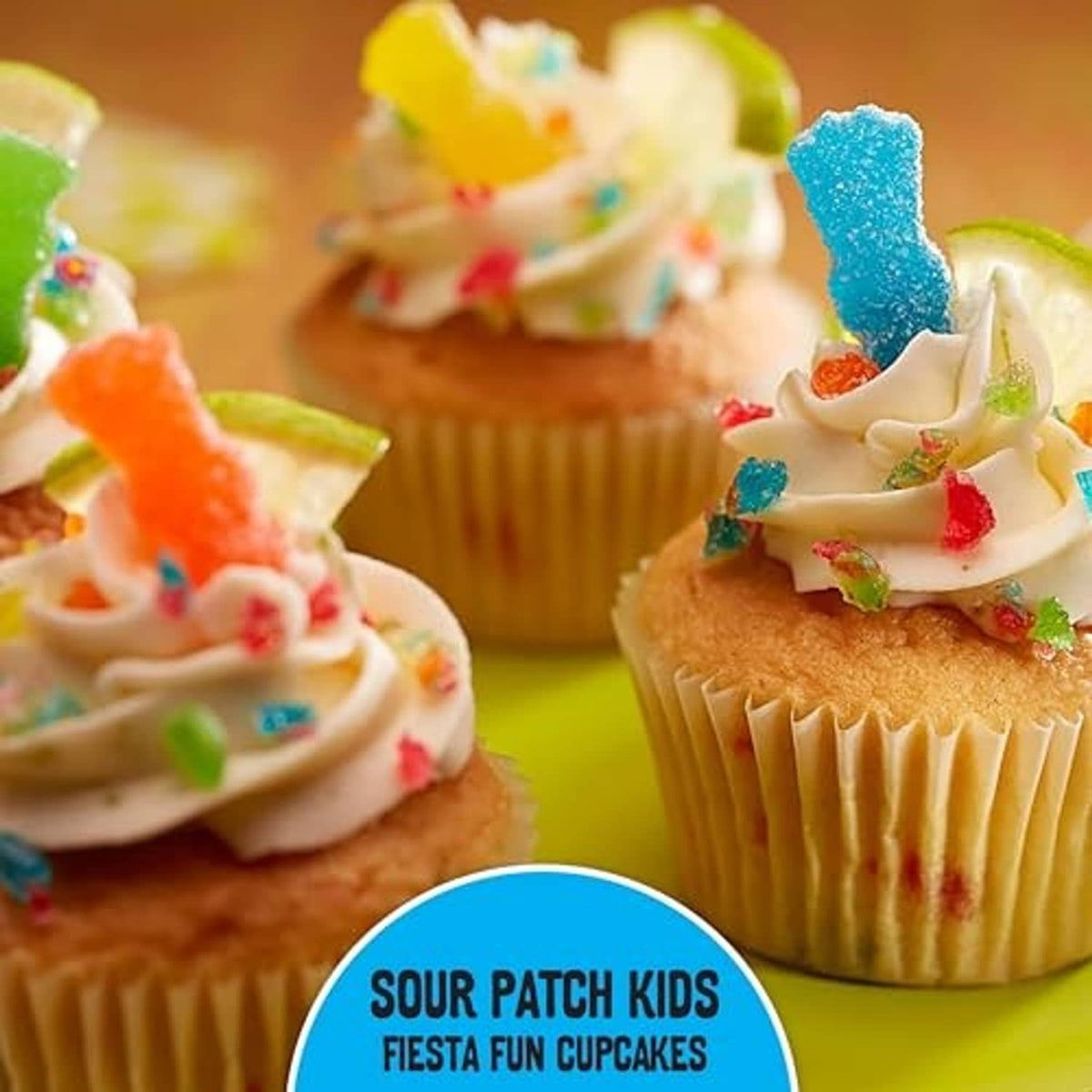 Sour gummy candy toppers on frosted cupcakes in blue, red, and green