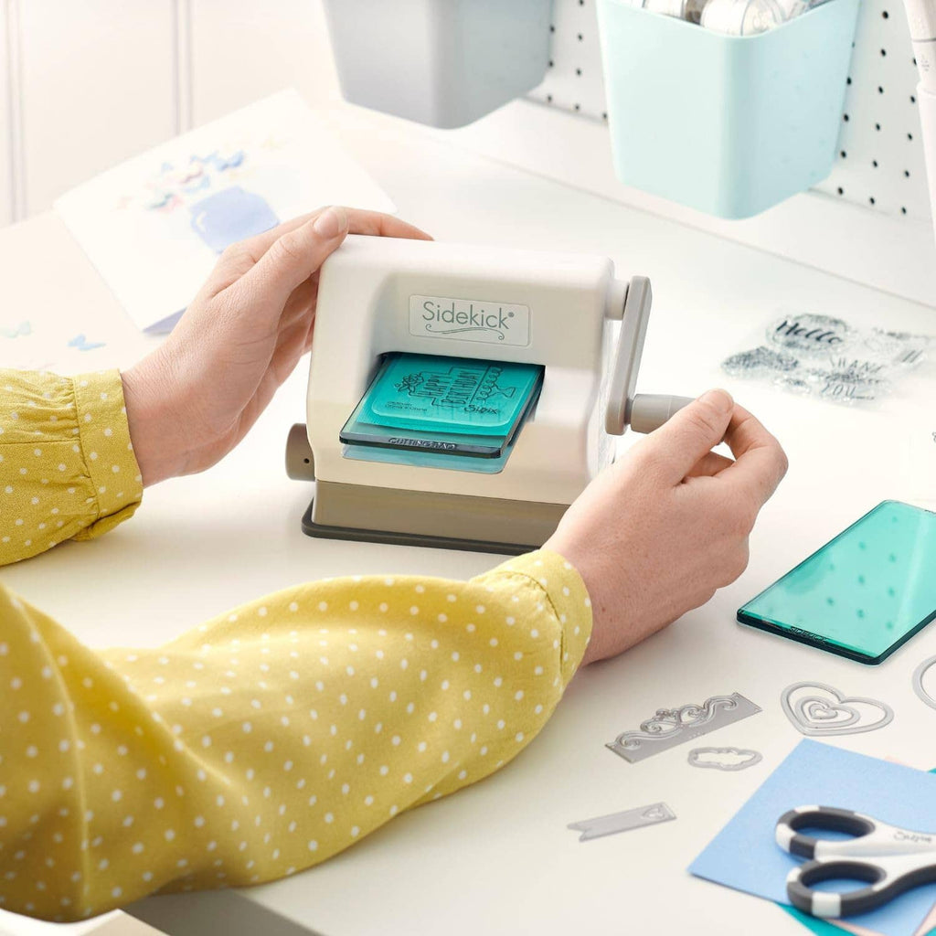 Hands loading teal plate into white die-cutting and embossing machine