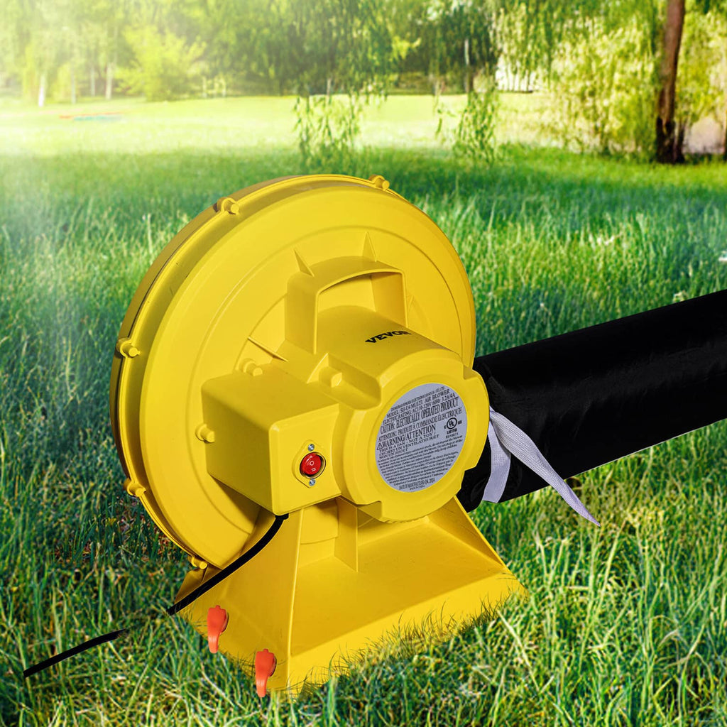 Yellow blower pump fan attached to an inflatable hose on outdoor grass