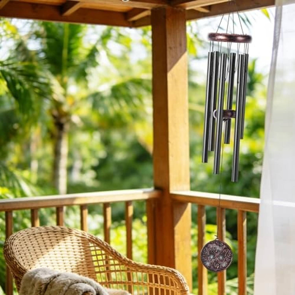 Copper-toned wind chime hanging from porch with butterfly medallion and six tubes
