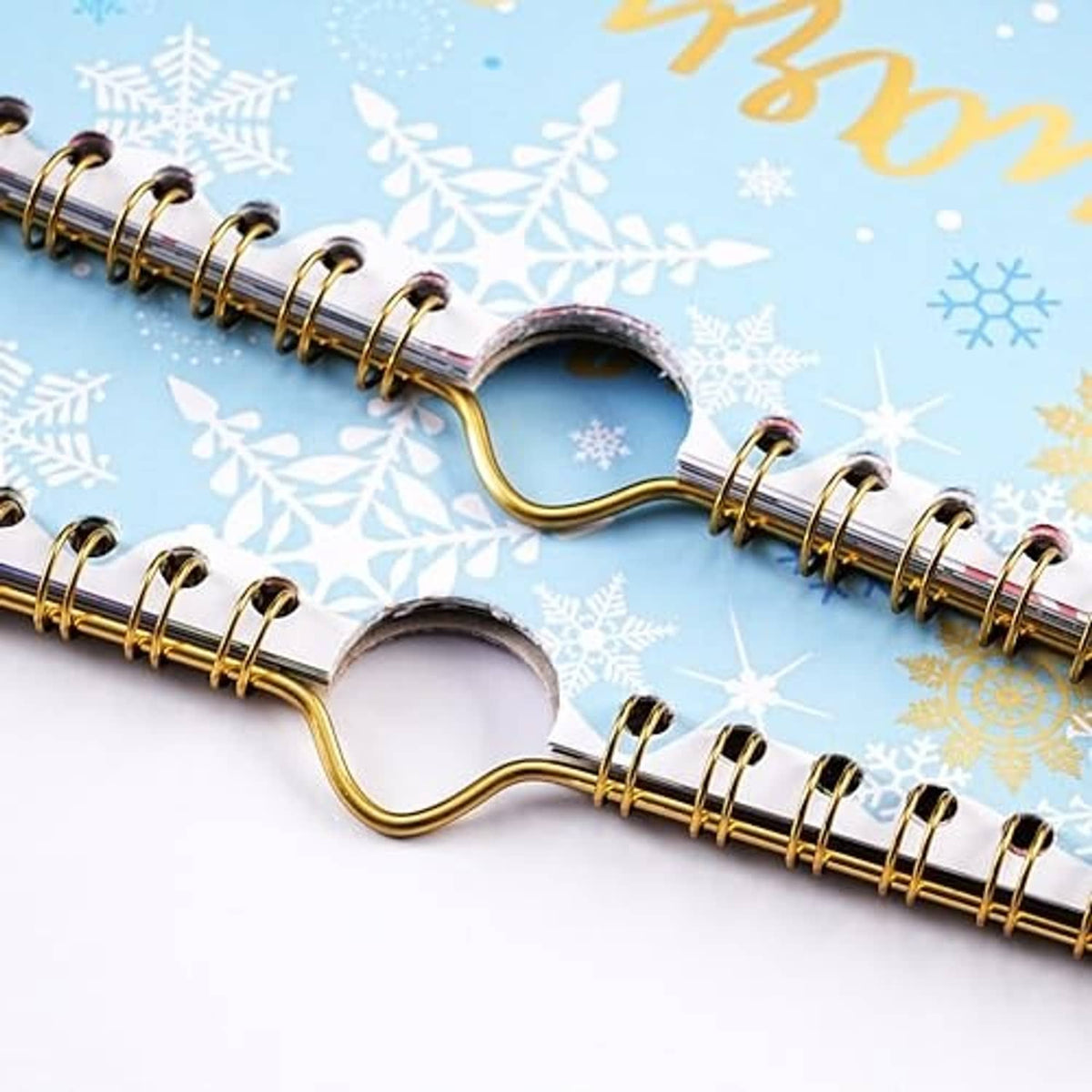 Gold metal spiral binding on blue calendar cover with visible hooks and snowflake pattern