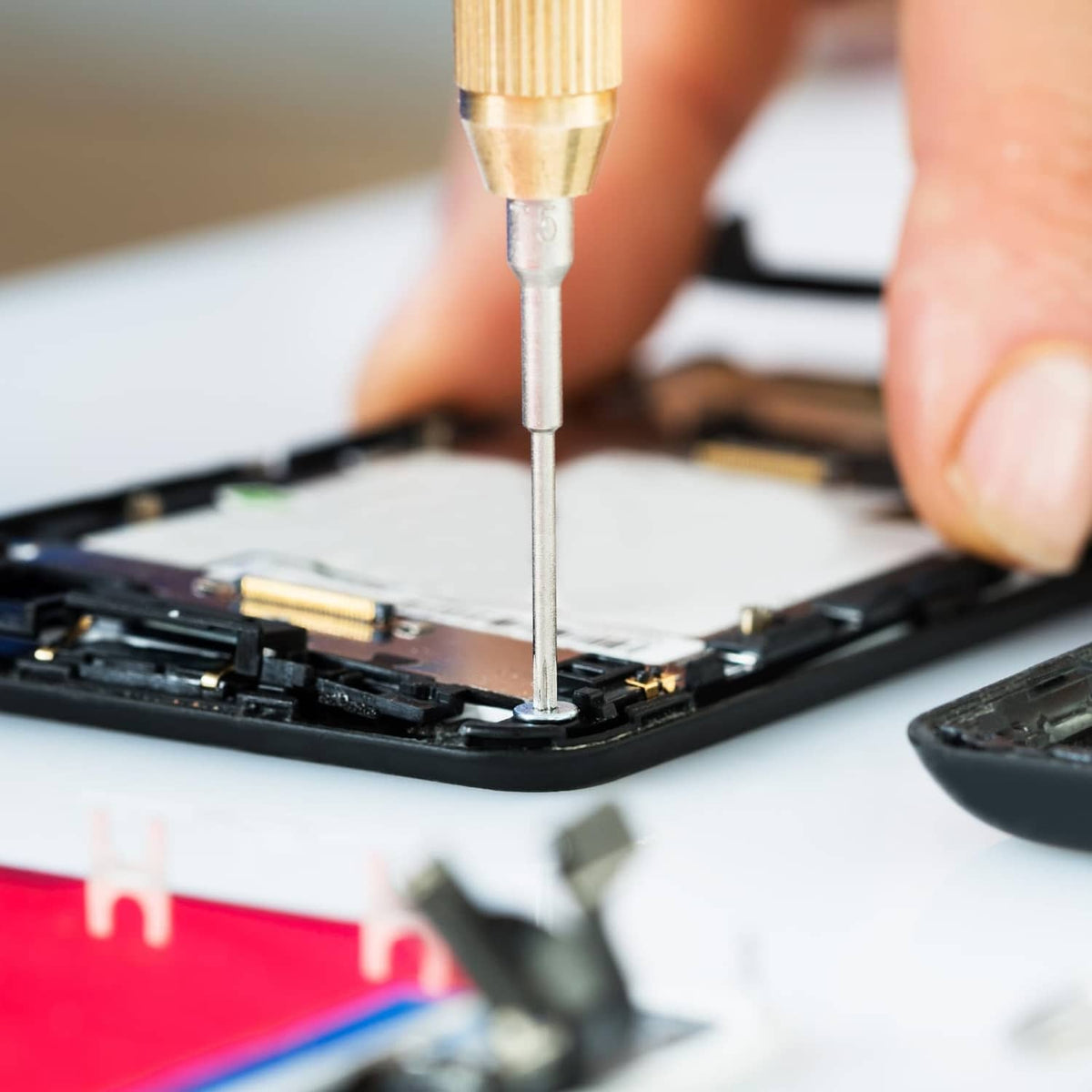 Phillips screwdriver bit inserted into a small screw on an electronics device