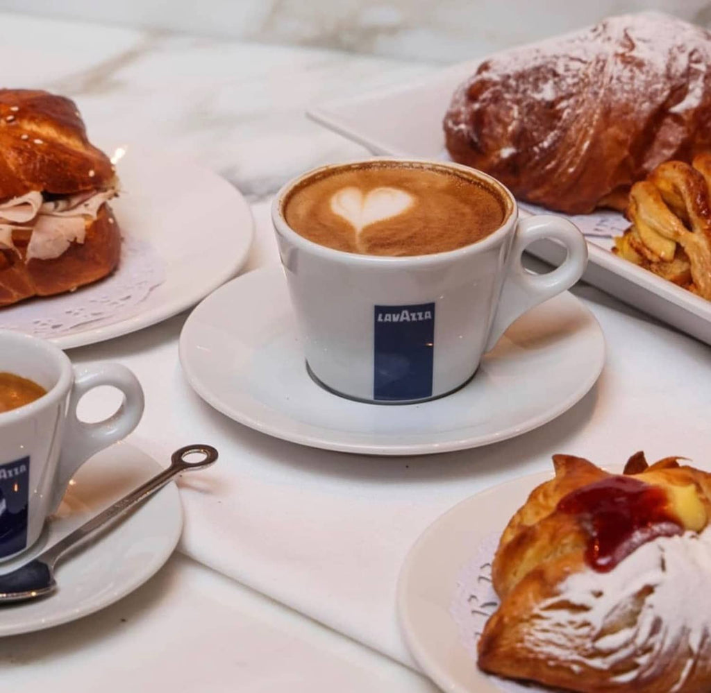 Lavazza coffee cup with latte art and pastries on a table