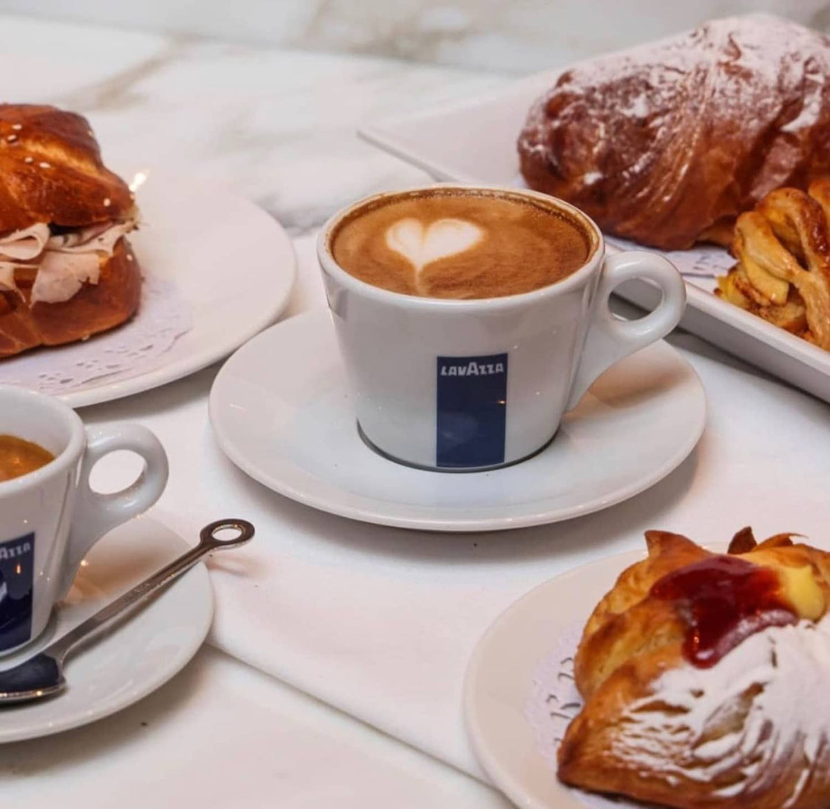 Lavazza coffee cup with latte art and pastries on a table
