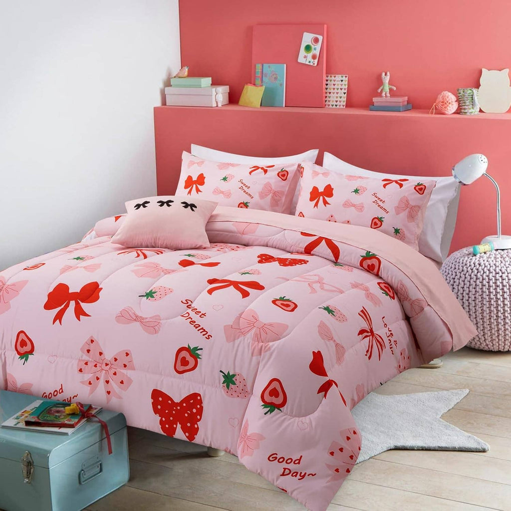 Pink bow print comforter set on a bed with matching pillows and sheet set