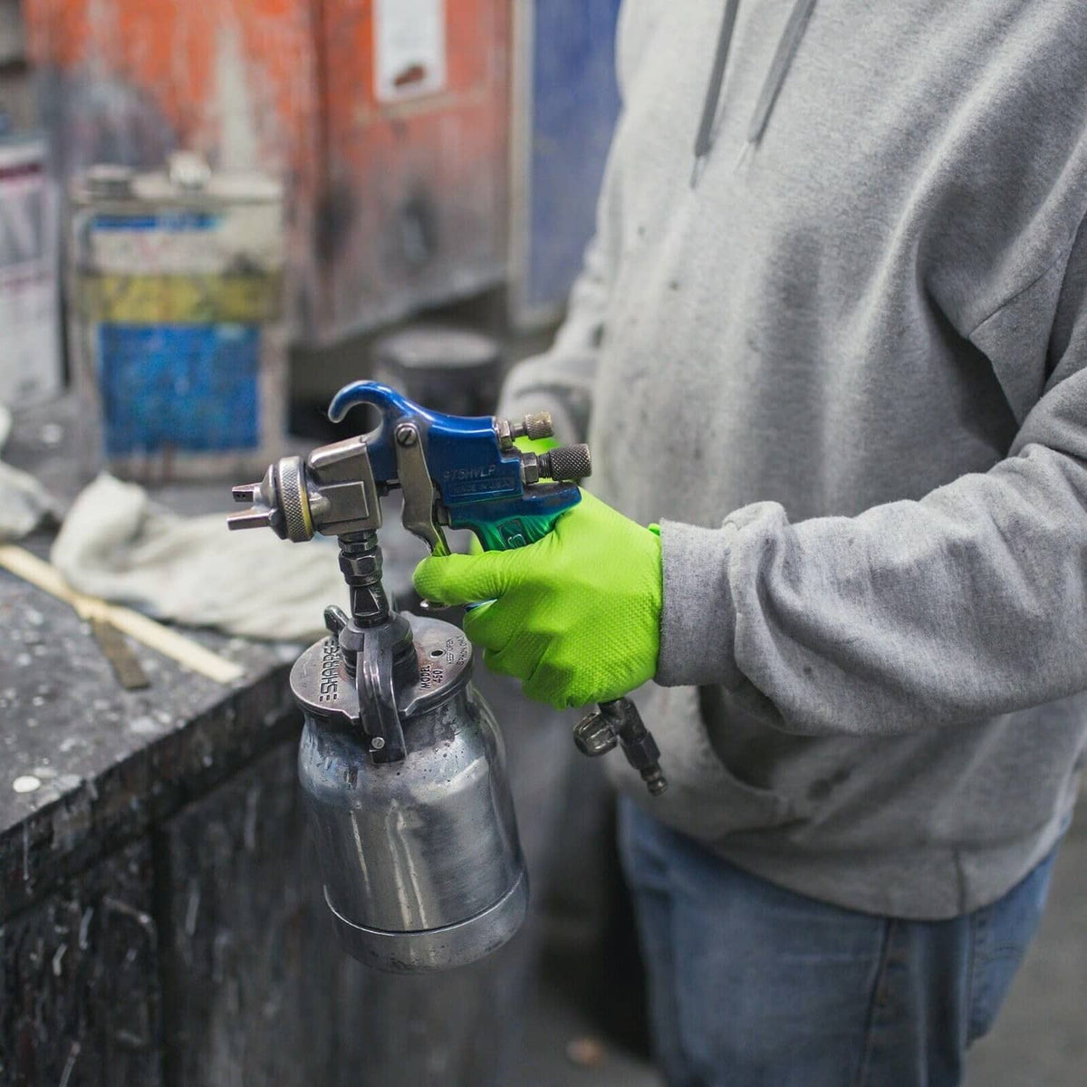 Green nitrile glove with textured grip holding spray gun