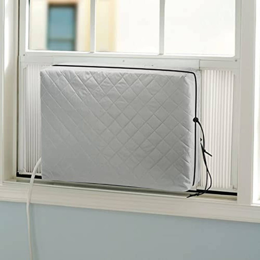 Grey quilted window AC unit cover with elastic straps and black securing cords.