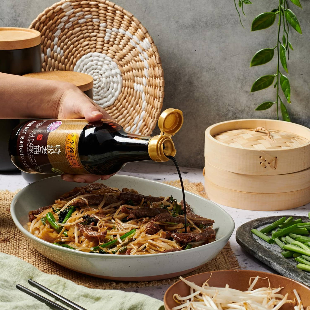 Lee Kum Kee dark soy sauce bottle pouring over stir-fried noodles