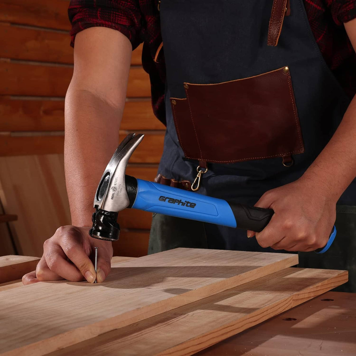 Graphite claw framing hammer with blue handle in use on wooden board