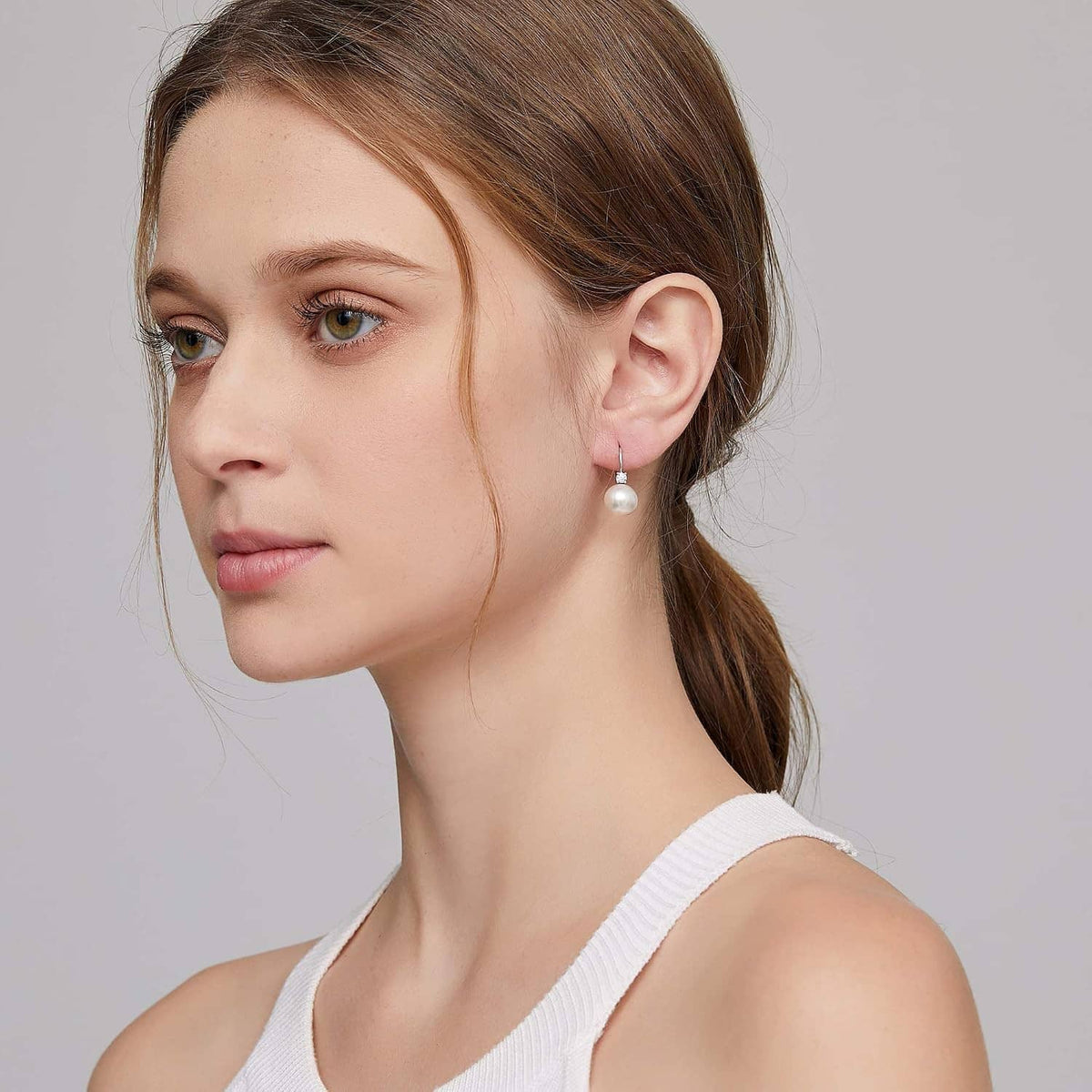 Sterling silver pearl leverback earrings on model: round white pearl with clear crystal top
