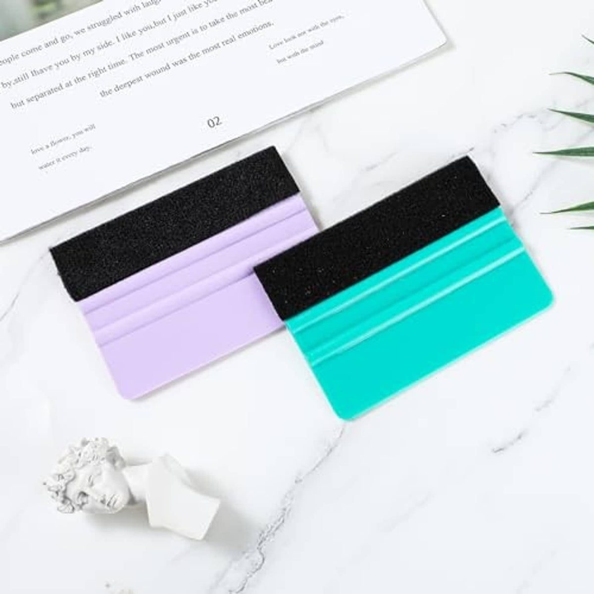 Two vinyl squeegees with black felt pads and turquoise and purple handles