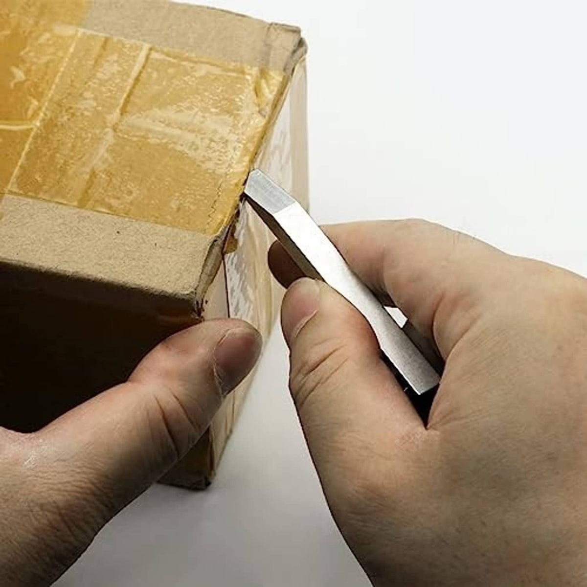 Mini metal prybar in hand prying open a cardboard box flap