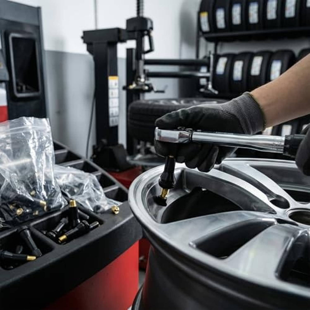 Technician installing tire valve stems using a tire machine and tools