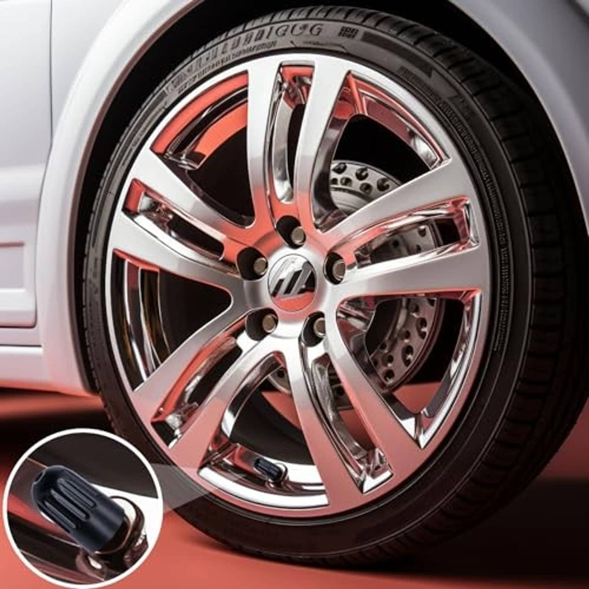 Black TPMS long-stem tire valve cap shown near a chrome wheel