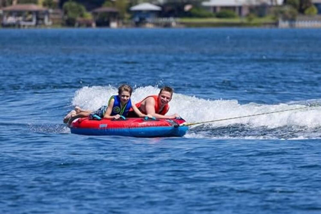 Two-person red and blue towable boat tube with two riders on open water