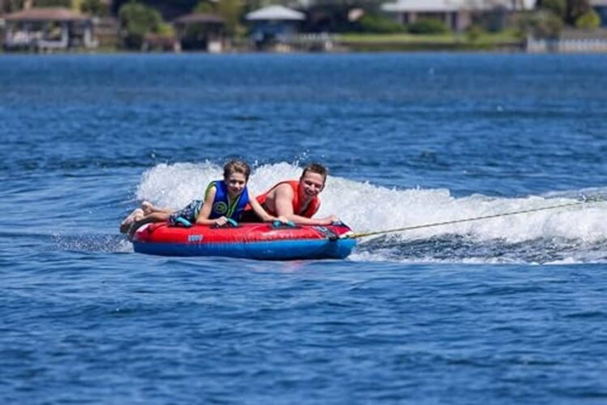 Two-person red and blue towable boat tube with two riders on open water