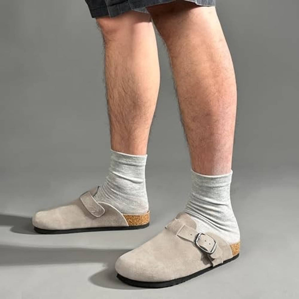 Taupe suede arch-support clogs worn with light gray socks, metal buckle strap