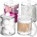 Clear apothecary canisters with lids holding cotton balls and cotton swabs