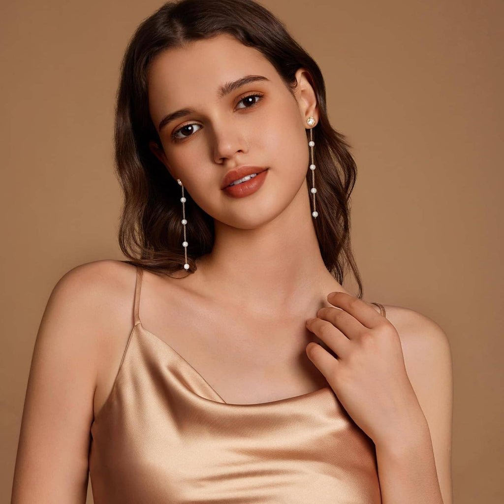 Long gold pearl drop earrings with white pearls on woman