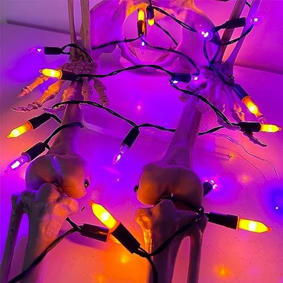 Close-up of glowing orange and purple mini LED string lights on black wire