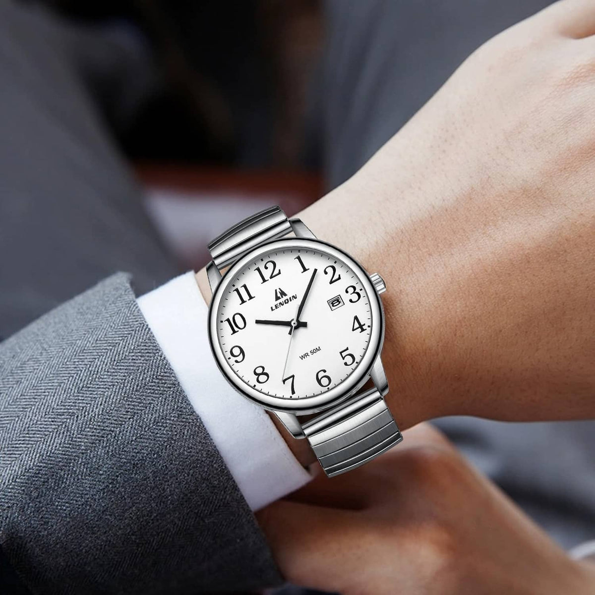 Mens analog quartz watch on wrist with silver metal strap and white dial