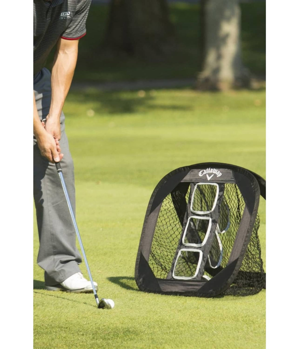 Black collapsible golf chipping net set up on grass for chipping practice