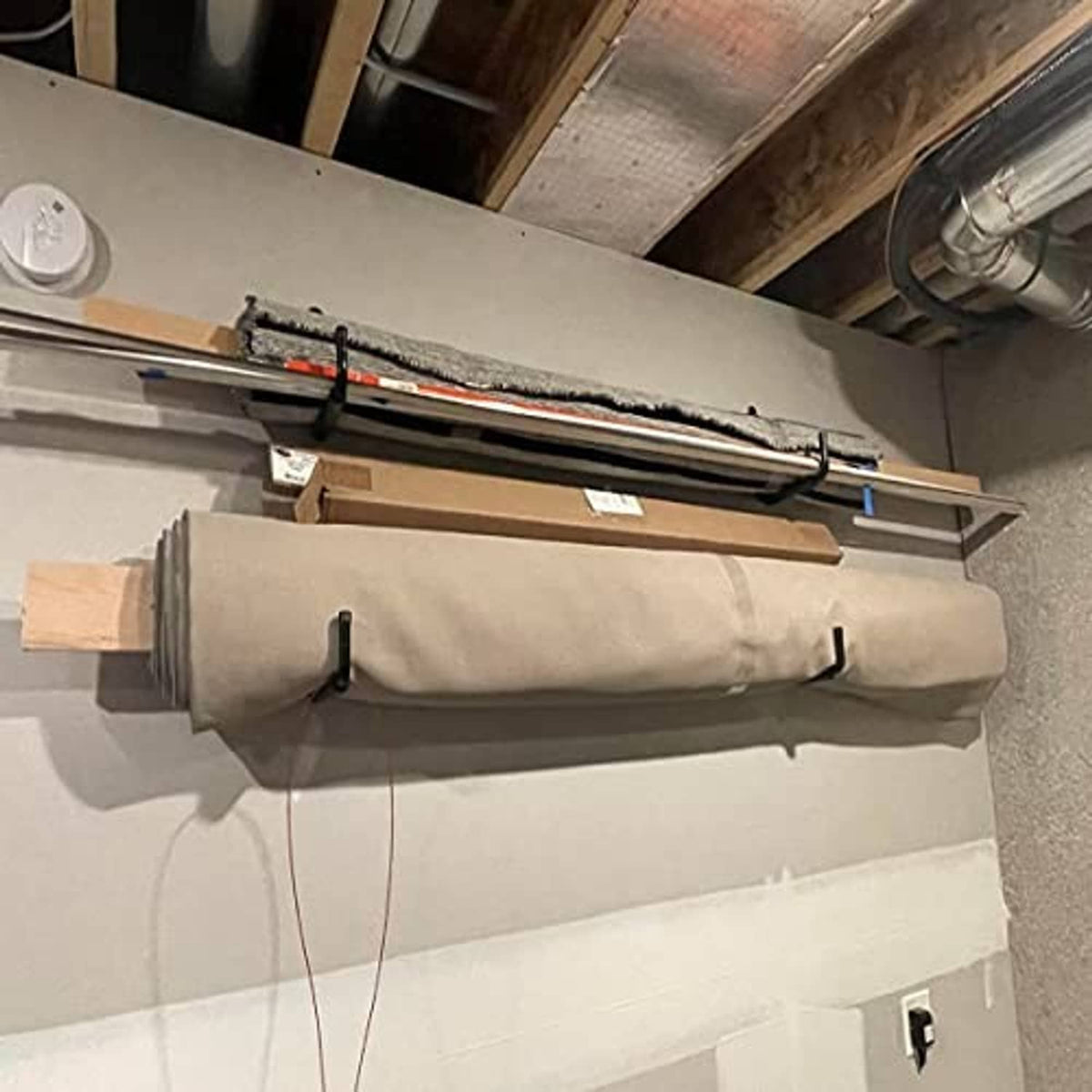 Wall-mounted garage hooks on a workbench holding long handled tools