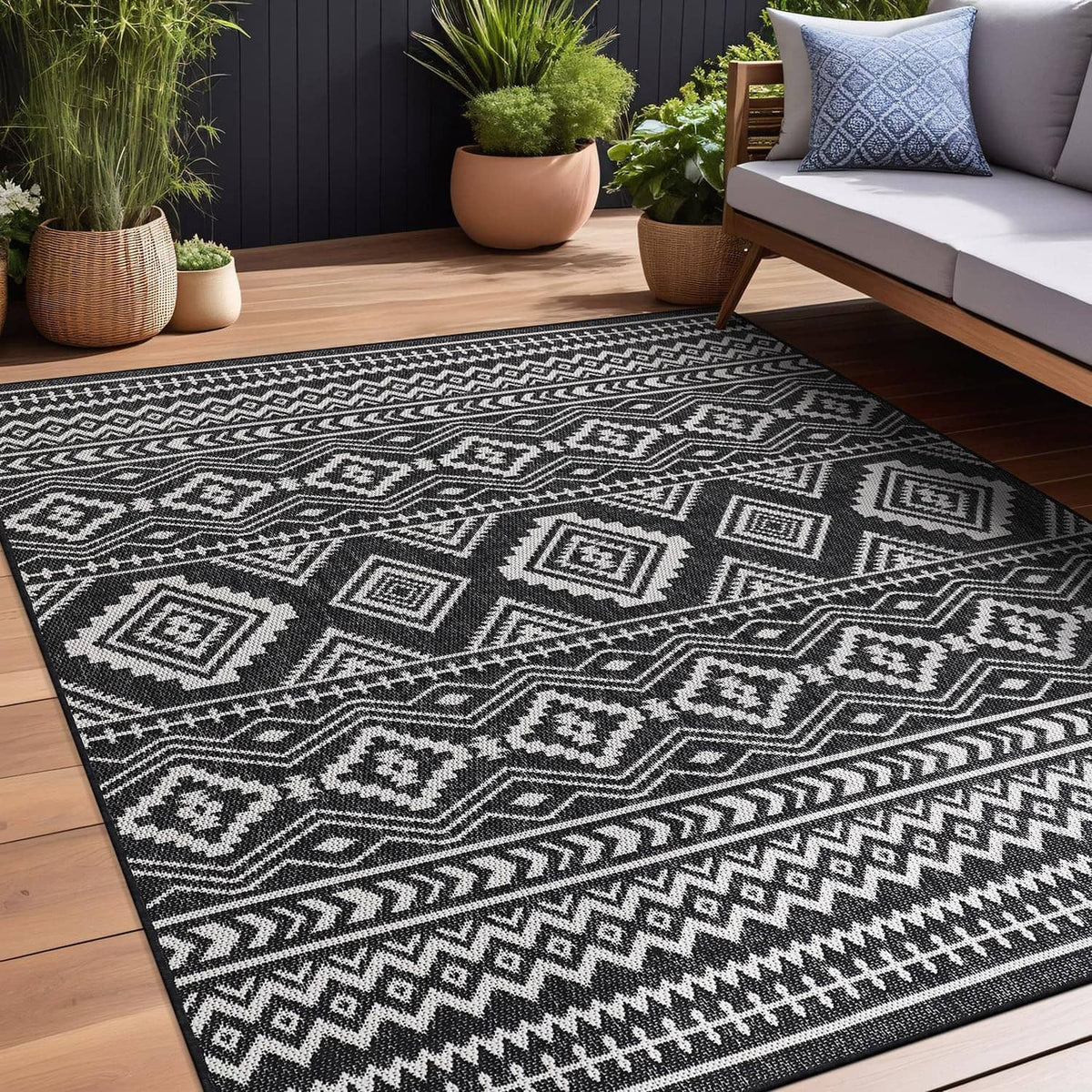 Large black-and-white geometric outdoor rug with repeating diamond motifs