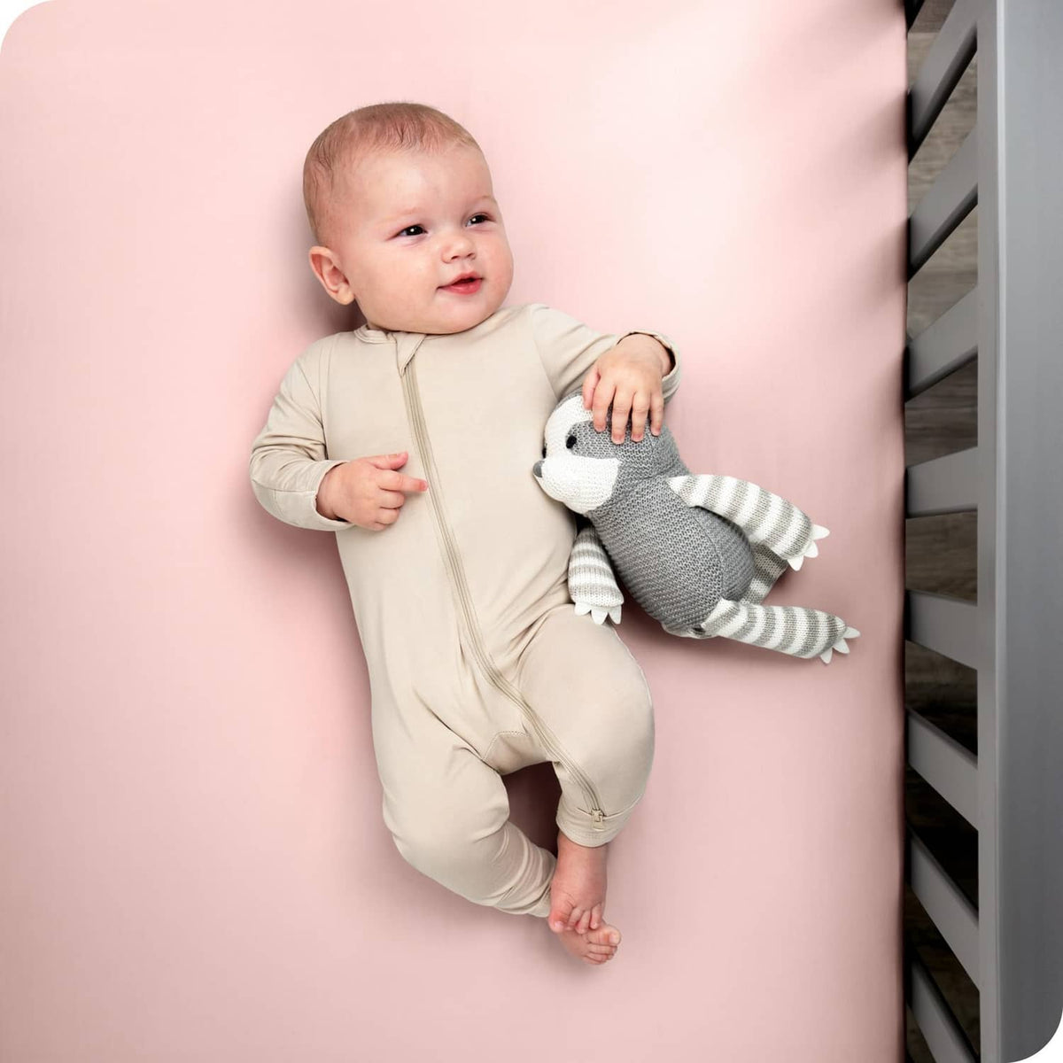 Pink crib fitted sheet on crib mattress, baby lying against the pink surface