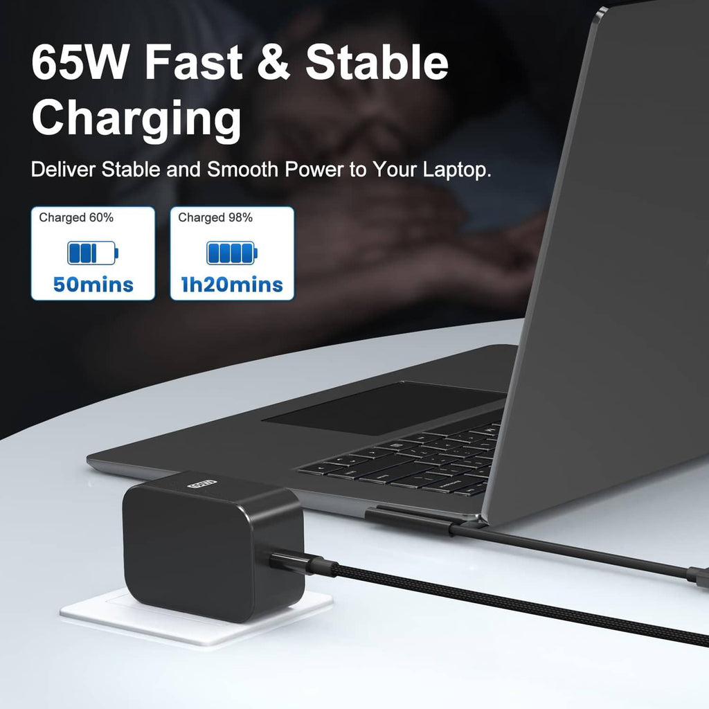 Black 65W charger brick with braided cable next to open laptop