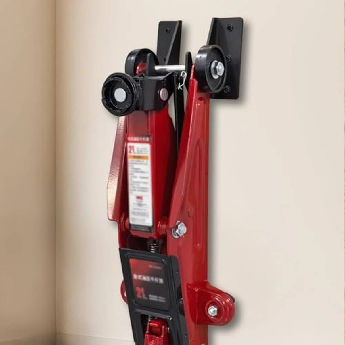Wall-mounted jack stand bracket holding a red hydraulic jack