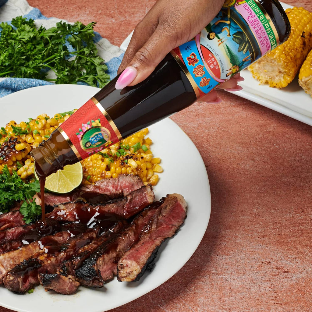 Oyster sauce bottle pouring over steak, corn, and herbs on a plate