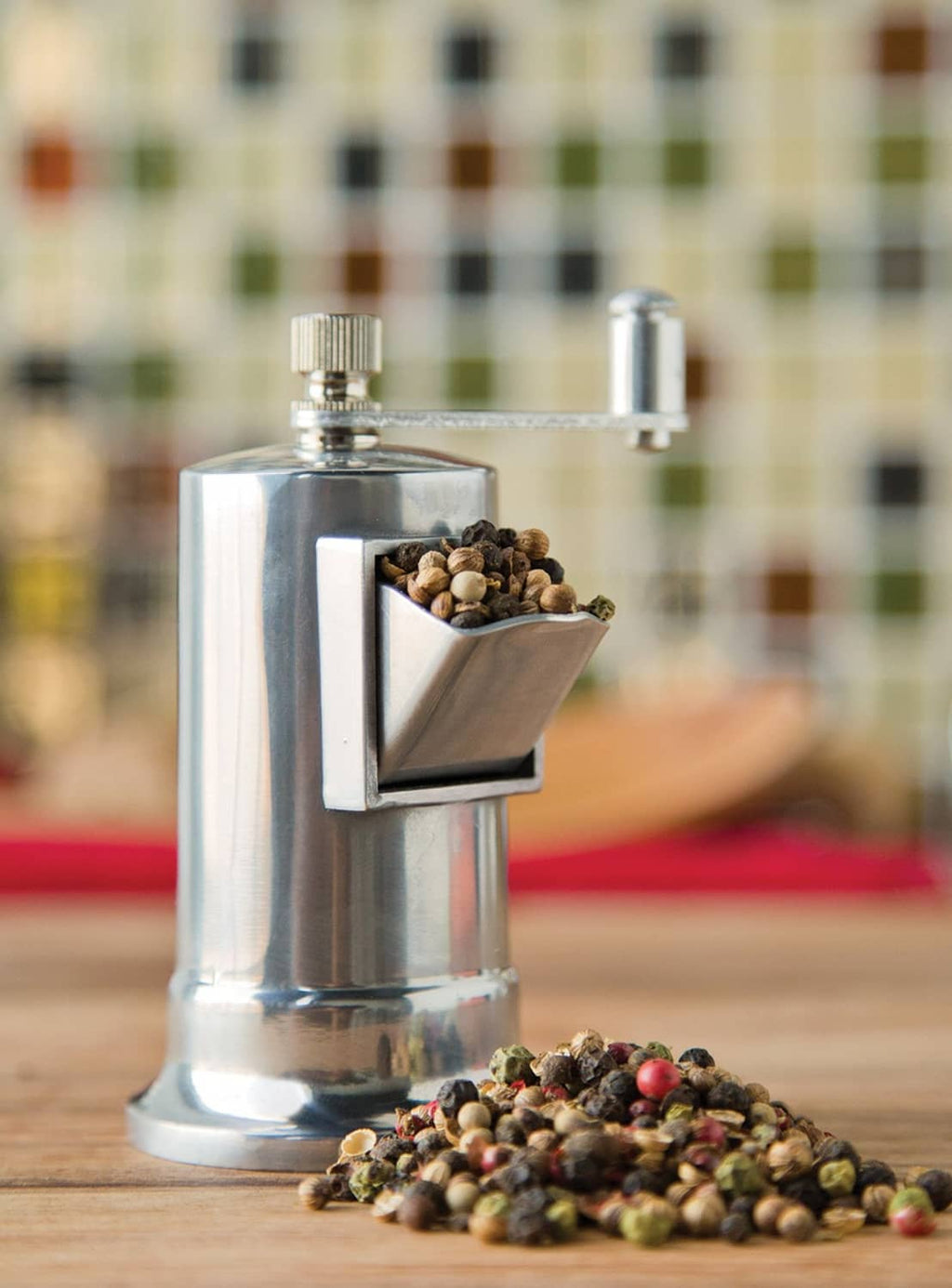 Manual stainless steel spice mill with tray holding mixed peppercorns at chute