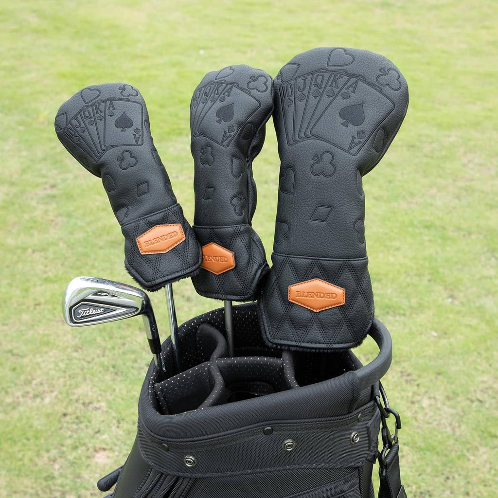 Set of three black golf club head covers with poker pattern and tan logo patches.