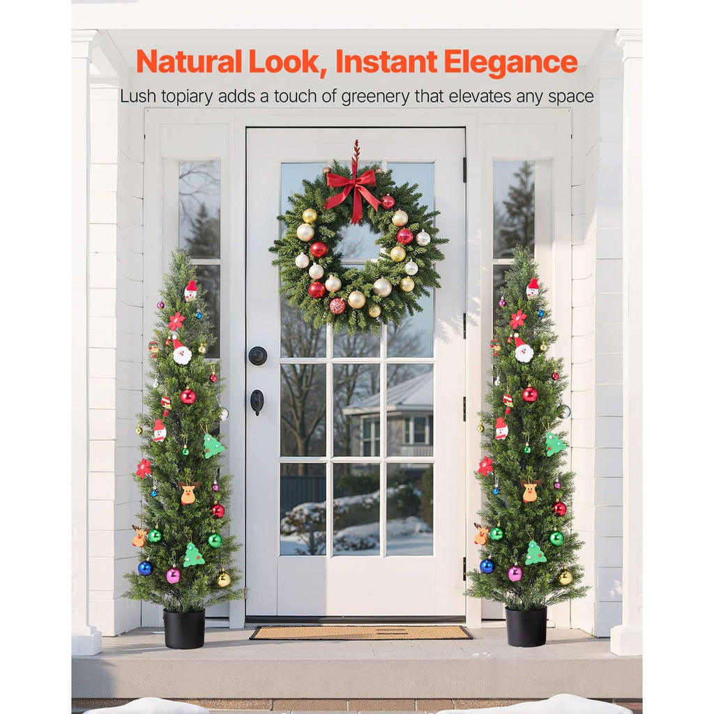 Pair of decorated artificial cedar trees in black pots with colorful ornaments