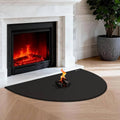 Black half-round fireplace hearth mat placed in front of a burning firebox