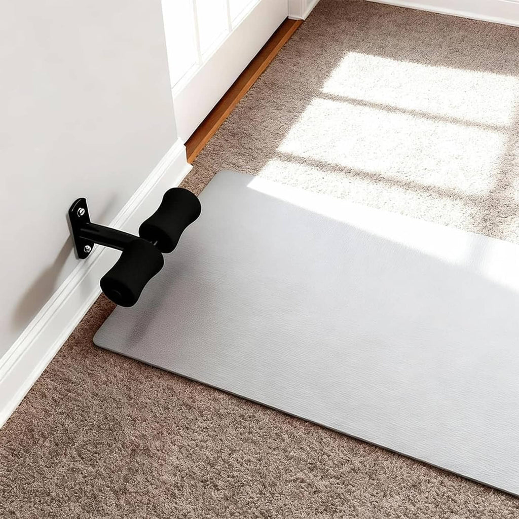 Wall-mounted sit-up foot holder installed on a wall with black foam rollers.